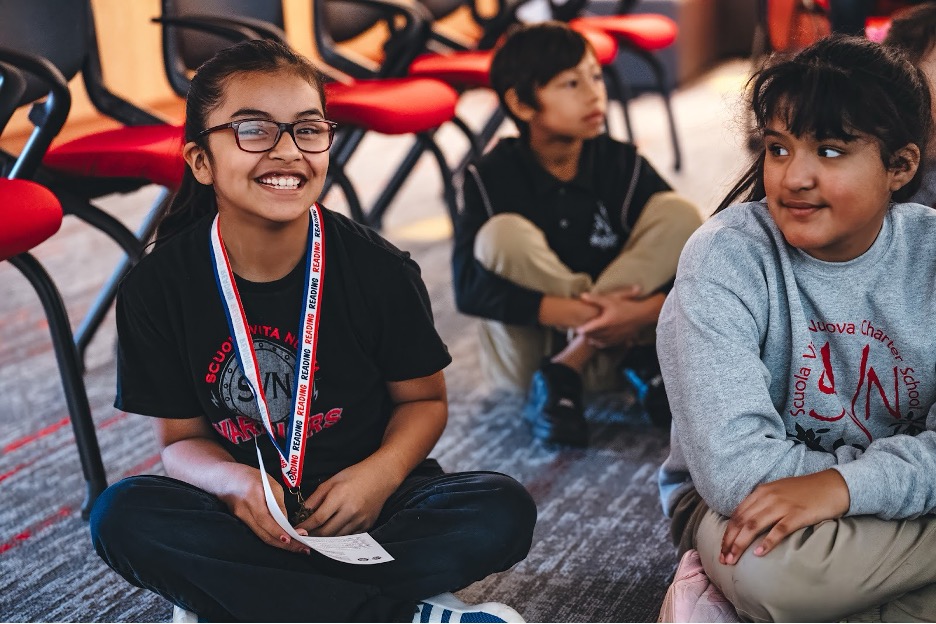 A student sitting on the floor at a reading event.