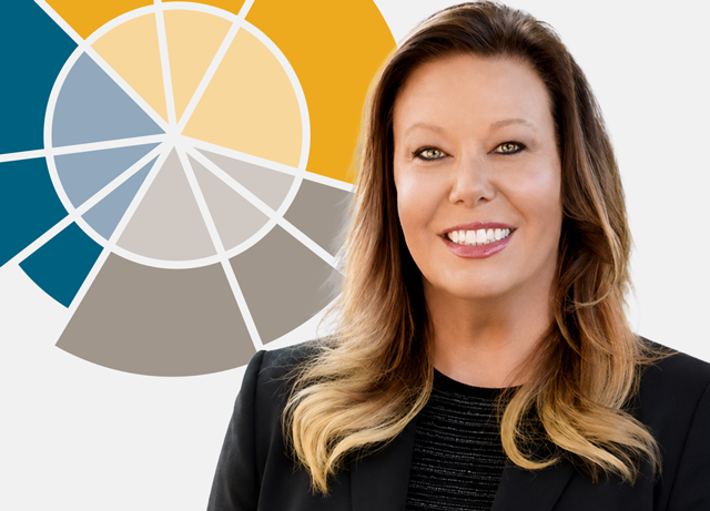 Portrait of a smiling businesswoman in a black blazer, with a multicolor circular color-wheel graphic behind her.